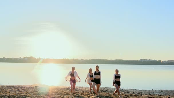 Dansföreställning av fyra tjejer på sandstrand nära sjön i gryningen — Stockvideo