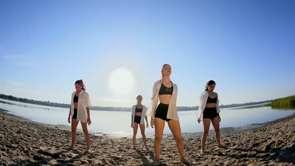 Actuación de baile de cuatro chicas en la playa de arena cerca del lago al amanecer — Vídeo de stock