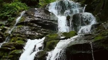 Art arda sıralı şelale orman arasında dağlar taşlar üzerinde sıçrama. Ağır çekim.