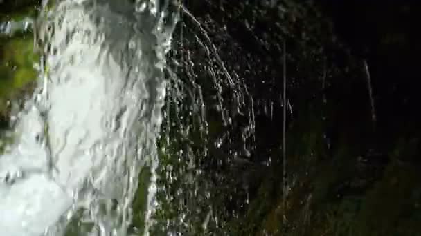 Kijk onder de waterval splash op stenen in het bos tussen de bergen. Slow motion. — Stockvideo