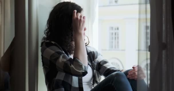 Jeune femme assise sur le rebord de la fenêtre et bénéficiant d'une vue sur la vieille ville. Silhouette de détente Fille à l'air frais à la maison — Video