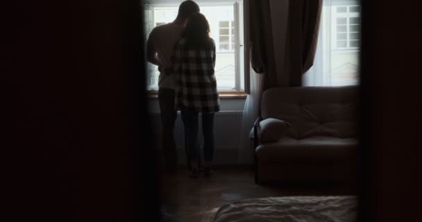 Genç bir çift, evdeki pencerenin yanında kalıyor. Mutlu genç aşıklar evde birlikte vakit geçirmenin tadını çıkarırlar. — Stok video