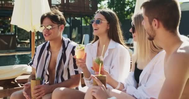 Baráti társaság, akik jól érzik magukat a medencében. Az emberek nyári koktélokat isznak a trópusi nyaraláson lévő luxushotelben. Sunny party koccintó szemüveg gyümölcs koktélok közelében uszoda — Stock videók