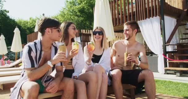 Groupe d'amis s'amuser à la piscine. Les gens encouragent boire des cocktails d'été à l'hôtel de luxe en vacances tropicales. Verres à clinquer ensoleillés avec cocktails de fruits près de la piscine — Video