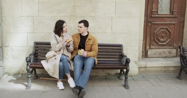 Az édes pár a régi európai városban vakációzik. A boldog fiatal szerelmesek élvezik az együtt töltött időt. Étkezés a padon helyi street food