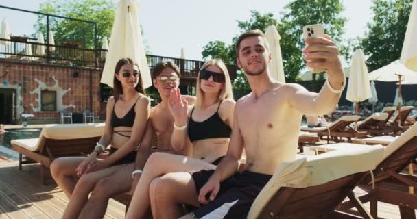 Groupe d'amis s'amuser à la piscine. Prendre selfie sur smartphone assis ensemble au bord de la piscine. Fête d'été près de la piscine — Video