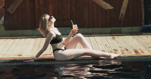 Las mujeres en traje de baño sexy se relajan cerca de la piscina. Viajar y tener vacaciones en el hotel de lujo. Chica con bebida alcohólica divertirse en el complejo vacacional — Vídeo de stock