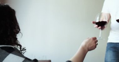 Romantik çift başarıyı kırmızı şarapla kutluyor. Başarılı bir aile kanepenin oturma odasında alkol içiyor. Yakışıklı adam karısına şarap getiriyor.