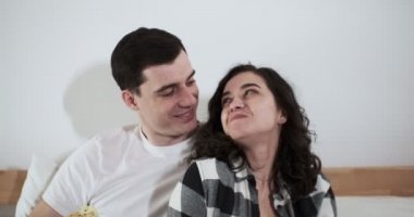 Mutlu bir erkek ve kadın evde bir yatakta pizza yiyorlar. Mutlu genç aşıklar birlikte vakit geçirmekten zevk alırlar.
