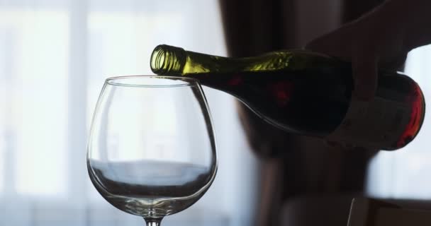 Egy közeli kép a borospohárról vörösborral, szuper lassított felvételen. Vörös bort öntök a serlegbe. A vörösbor gyönyörű hullámot alkot az üvegben. — Stock videók