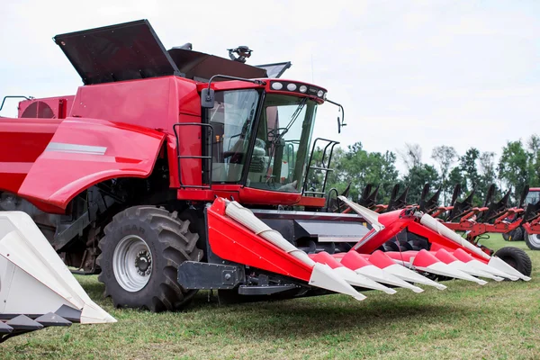Ein moderner, roter Traktor pflügt im Frühjahr auf einem grünen Acker auf dem Hof. Erntemaschine sät Weizen. — Stockfoto