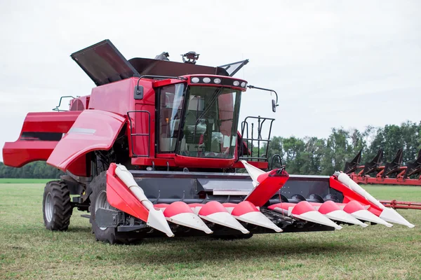 Moderno trattore rosso tecnologia arare un campo agricolo verde in primavera in azienda. Semina di frumento. — Foto Stock