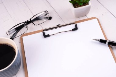 Boş dosya, kalem, gözlük ve bir fincan kahve.