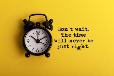 Çalar saat ve ilham verici alıntılar. Zaman hiçbir zaman doğru olmayacak. Sarı arkaplan