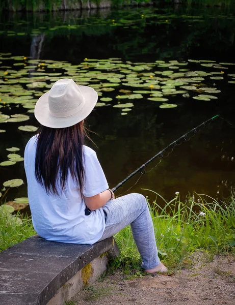 Ung kvinna fiskar i dammen i sommar — Stockfoto