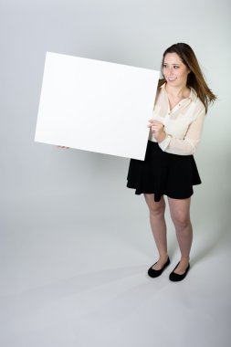 Boş işaret tutan gülümseyen genç kadın