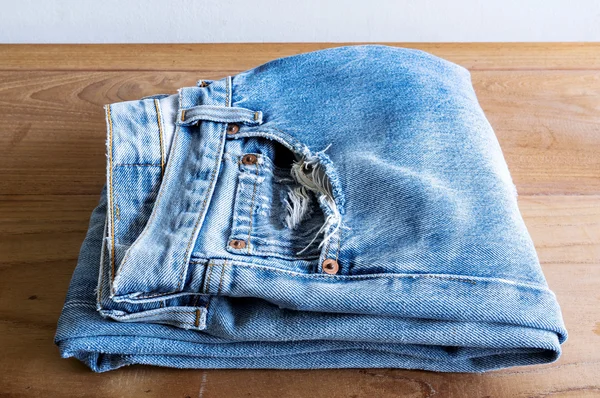 Stack of blue jeans on wooden table. — Stock Photo, Image