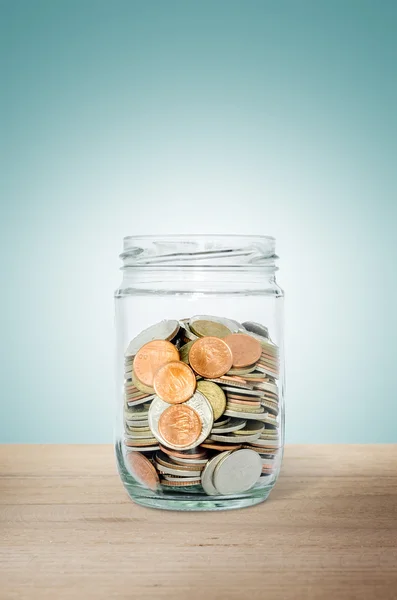 Soldi nella bottiglia di vetro sul tavolo di legno. Risparmiare denaro concetto . — Foto Stock