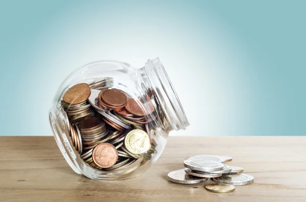 Soldi nella bottiglia di vetro sul tavolo di legno. Risparmiare denaro concetto . — Foto Stock
