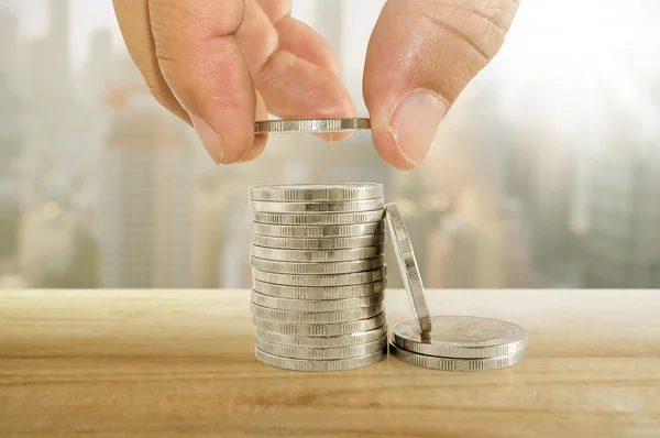 Risparmio di denaro concetto. mano mettendo moneta a pile di monete . — Foto Stock