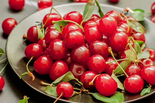 Black plate with delicious, juicy, bright cherries — Stock Photo, Image