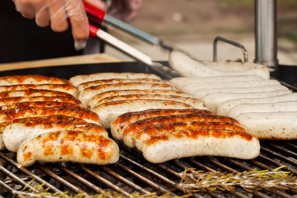 Ręka z łopatką przerzuca kiełbasy do hot dogów — Zdjęcie stockowe