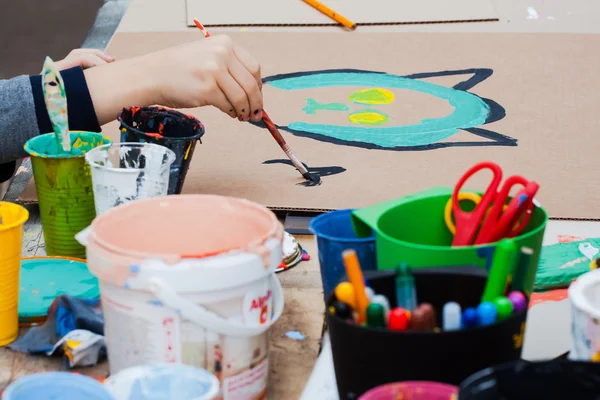 Criatividade infantil. Desenho à mão uma criança pinta. Latas de tinta na mesa — Fotografia de Stock