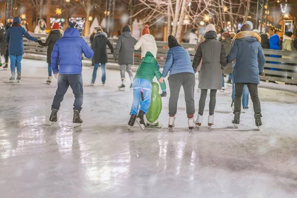 Christmas, winter and leisure concept, happy friends and families on skating rink, evening outdoor, holiday lights — Stock Photo, Image