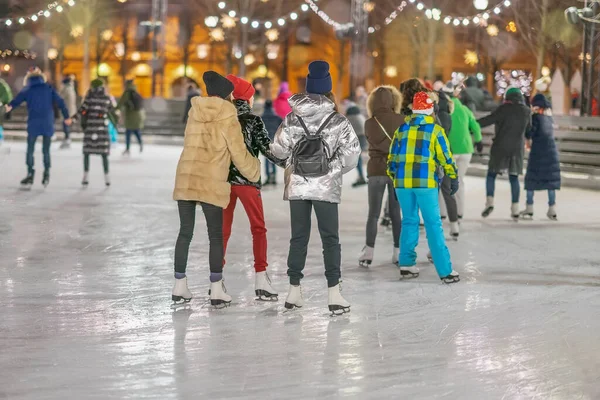 Happy Girlfriends ice skating on rink in city park. Healthy outdoor winter activity — Stock Photo, Image