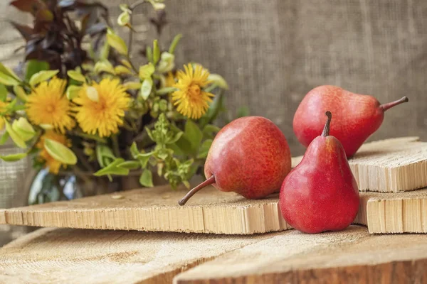 Tasty ripe organic red pears on natural wooden background and yellow flowers. Vegetarian, vegan, healthy diet food and harvest concept — Stock Photo, Image