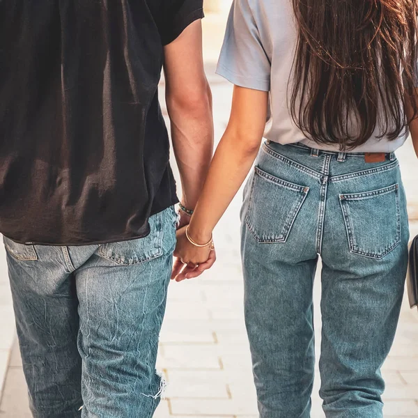 Mani in mano primo piano di coppia irriconoscibile da dietro, passeggiata romantica — Foto Stock