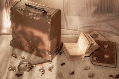 Tahta bir sandığın yanında eski kitaplar, büyüteç. Aydınlık ve gölge, sonbahar günü. Eski tarz. Nostalji kavramı, üzüntü.