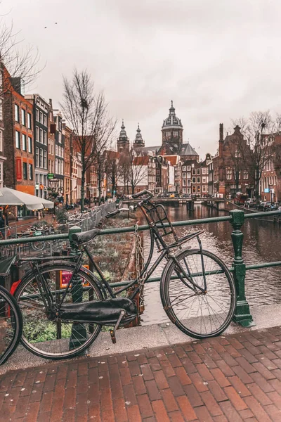 Bicycle parked on a bridge. Cloudy day in Amsterdam. Picturesque town landscape — Stock Photo, Image