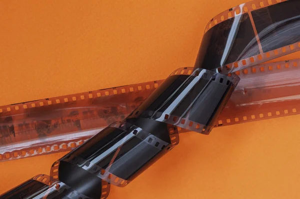 Old 35 mm Photographic film strips, negative on bright orange background, flat lay. Photo, movie cinema concept