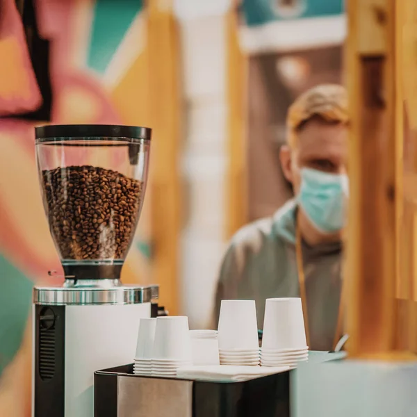 Máquina de café com grãos de café e linhas de cabeça para baixo copos de papel para café, fundo borrado do vendedor — Fotografia de Stock
