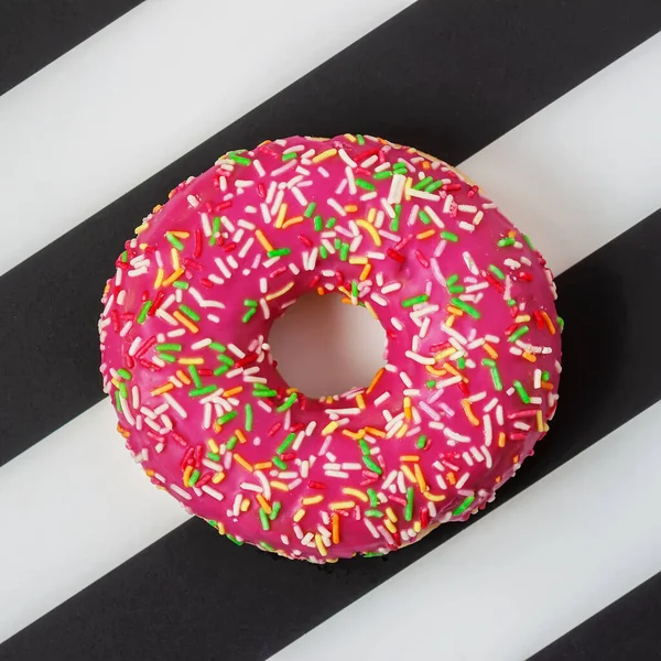 Hell glasierter rosa Donut mit Sahnehäubchen auf schwarz-weißem Minimalhintergrund, Draufsicht — Stockfoto