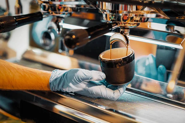 Mans Hände bereiten Kaffee zu, frischer Espresso ergießt sich in Porzellantasse. Kaffeekochen in der Kaffeemaschine. — Stockfoto