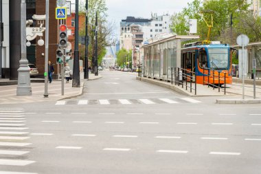 Boş kavşak ve tramvay durağı, trafik ışıkları ve yaya geçidi olan şehir caddesi manzarası