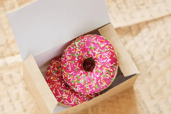 Zwei glasierte rosa Donuts in Pappschachtel in Großaufnahme. Süßigkeiten. Verkauf, Kauf, Lieferung von frischen Backwaren, Online-Shop — Stockfoto