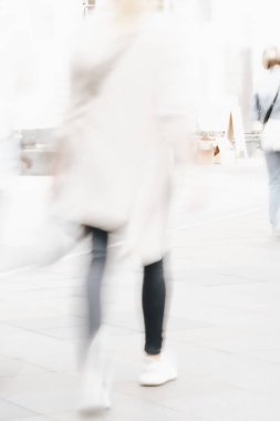 Şehir caddesinde yürüyen tanınamaz bir kızın soyut ve bulanık görüntüsü. Kentsel modern arka plan.