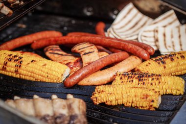 Process of preparing sausages and corn on Outdoor Grill.
