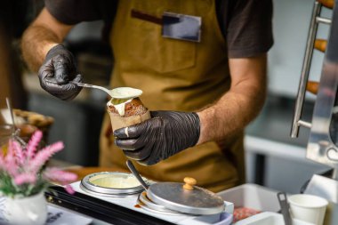 Male Hands of chef making Trdelnik. National street food, cake made out of sweet dough rolled around spit and grilled