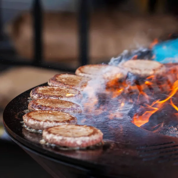 Burgers for hamburger prepared on bbq grill, barbecue outdoors with fire flame — Stock Fotó