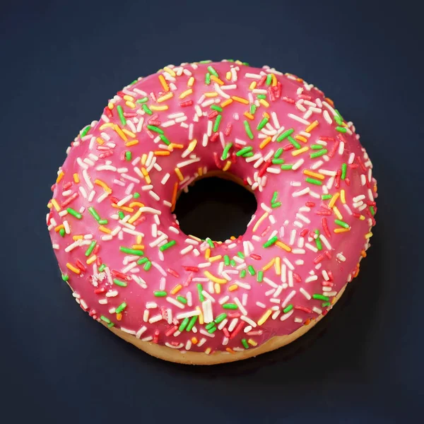 Rosafarbener, karamell glasierter Donut auf dunklem Hintergrund in Nahaufnahme — Stockfoto