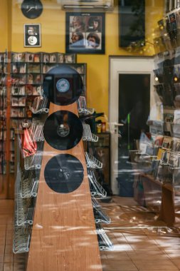 BURGAS, BULGARIA - 10 OCTOBER, 2025: Outside view of display case of vinyl records and CDs inside cozy music store, nostalgic atmosphere. Blurred background. Concept of vintage music, retro collection