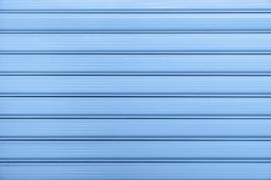 Mavi metal duvarın yatay çizgileri, pürüzsüz dokuyu ve marina renginin parlak yüzeyini gösteriyor. Yılın rengi, mevsimin rengi, modern tasarımda marina tonu