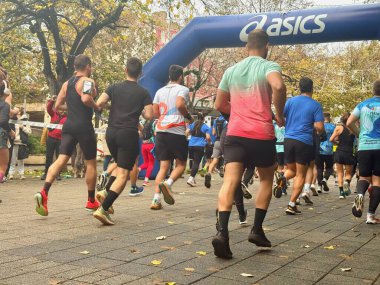 BURGAS, BULGARIA - NOVEMBER 09, 2025: Şehir maratonu sırasında şişme kemer altında yakalanan koşucular grubu. Spor anlayışı, dayanıklılık, aktif yaşam tarzı