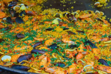 Paella büyük tavada pilav ve deniz ürünleri, açık hava yemek servisi, paella hazırlama, yemek pişirme, sokak mutfağı üretimi. Paella pişirme, deniz ürünleri pilavı, festival yemekleri, sokak yemekleri.