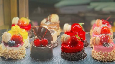 Pastanede renkli minyatür pastalar, çilek soslu vitrin, kurabiyeler, çikolata süslemeleri. Tatlı seçimi, tatlı pastane ürünleri, kafe menüsü, şekerleme işi.