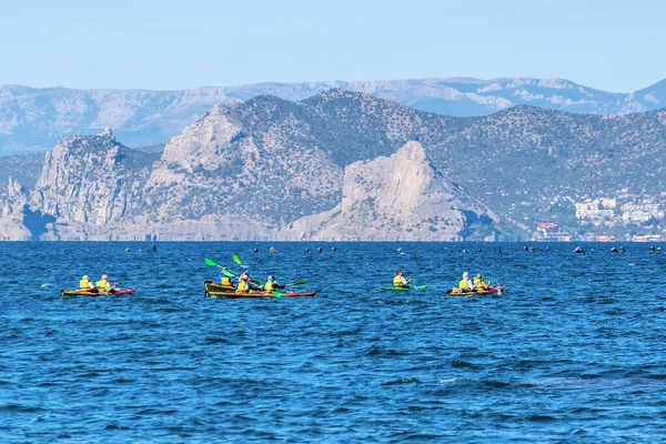 Sudak, Kırım - 9 Eylül 2020: Turistler Karadeniz 'de dağların arka planına ve Novy Svet köyüne karşı kanoyla açılıyorlar. Yumuşak odak